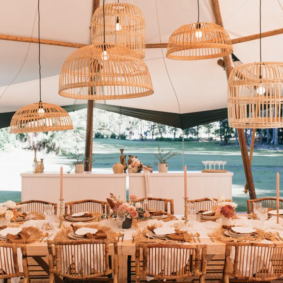 A table setting for a tipi wedding at The Acre featuring beautiful hanging installations and flowers.