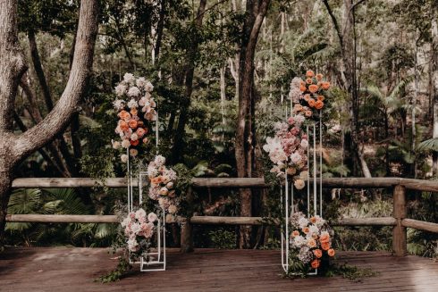 A wedding arbour on the ceremony deck with beautiful floral arrangements on both sides