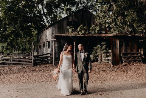 A briude and groom in front of an old wooden building at the acre