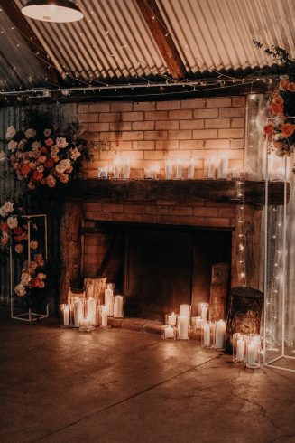 The beautiful fireplace inside the barn surrounded by candles