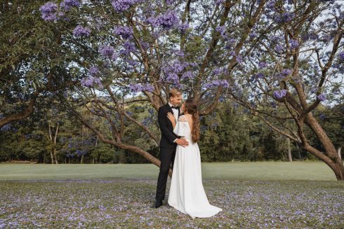 Bride + groom + purple jacaranda tree