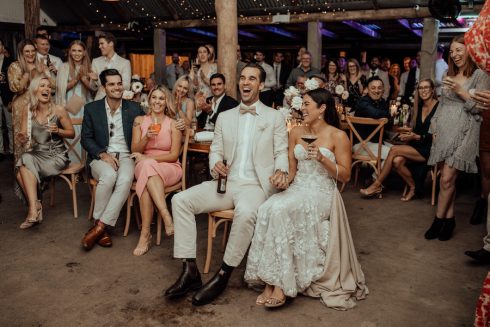 Bride + groom sitting with wedding guests